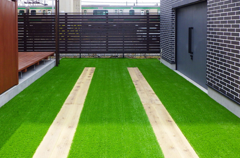 鹿沼市の新築駐車場｜人工芝＋枕木調平板の走行ライン｜段差ゼロ・排水勾配あり