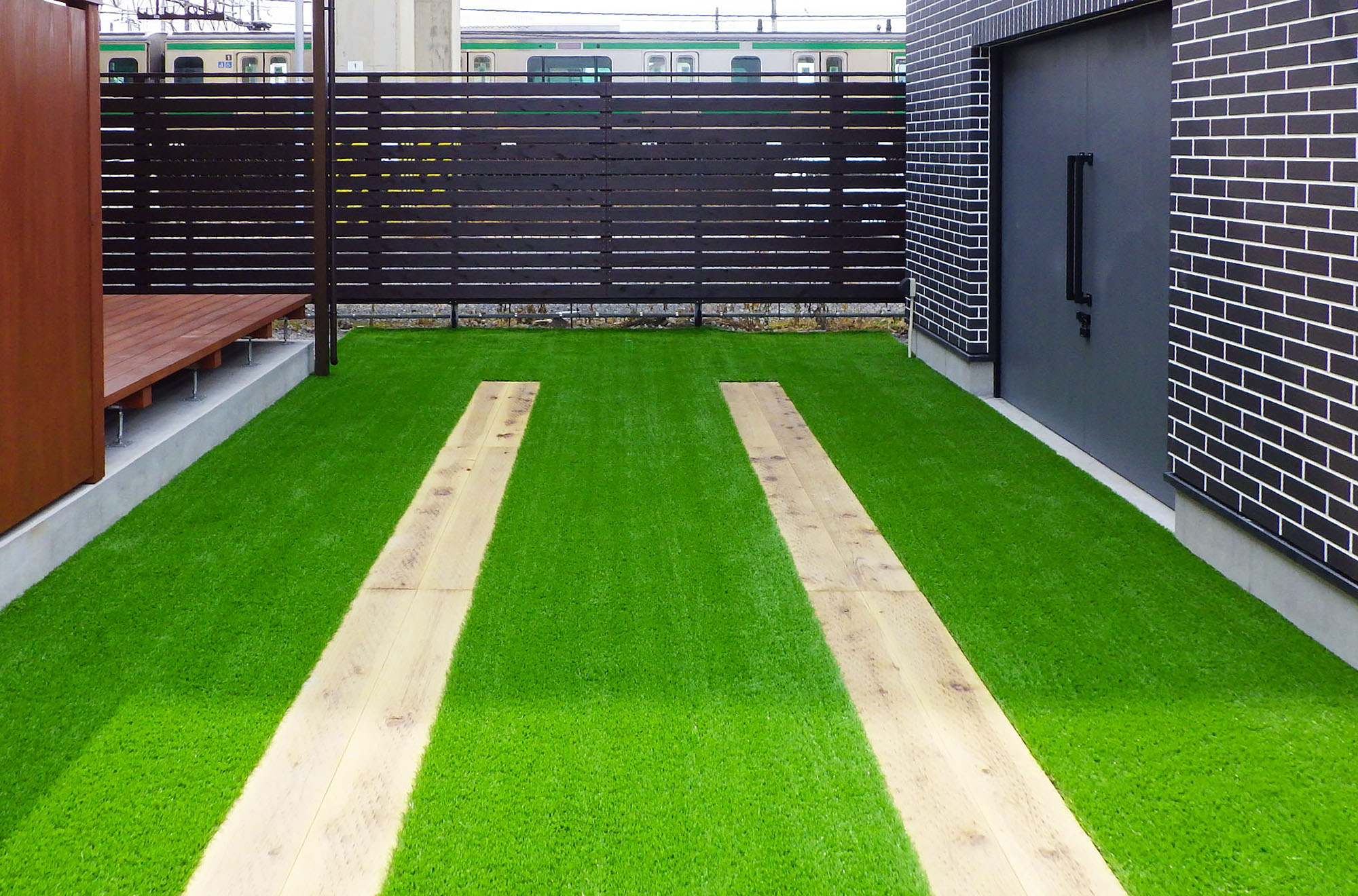 鹿沼市の新築駐車場｜人工芝＋枕木調平板の走行ライン｜段差ゼロ・排水勾配あり